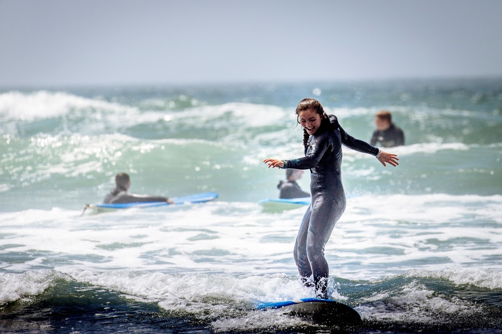 Teen cycling and surfing trip on pacific coast, summer adventure camp group