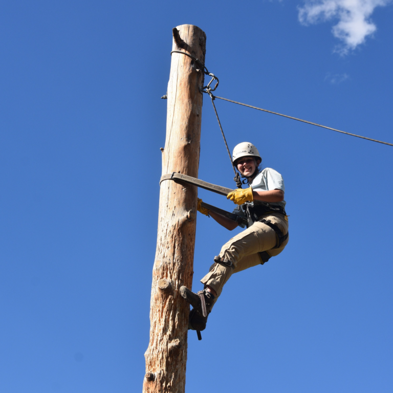 Emma climbing a telephone pole at Philmont Scout Ranch after going on a teen adventure trip with Apogee Adventures